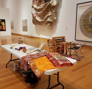 Photo from inside the Harn Museum of Art with a display of weavings and weaving tools.