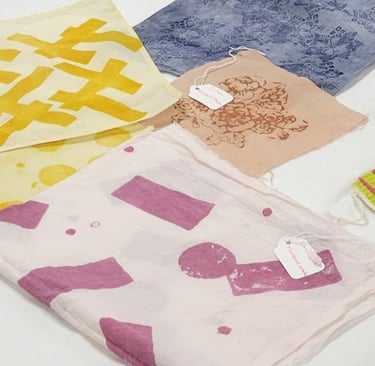 Block-print dyed fabrics of pink, yellow, brown, and blue.
