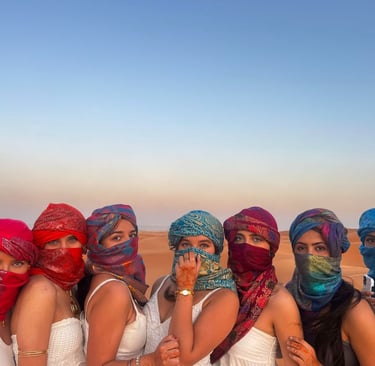 Mulheres brasileiras montado em camelos nas dunas do Deserto do Saara, pôr do sol.