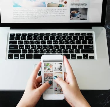 Manos utilizando un smartphone para navegar en un sitio optimizado para móviles frente a un portátil