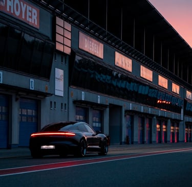 Black Porsche Taycan electric car parked on a race track pit lane at sunset.