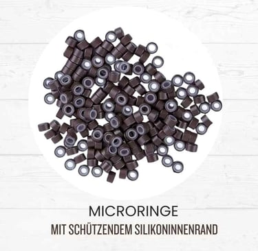 Dark brown silicone lined micro rings for hair extensions on a white wood background.