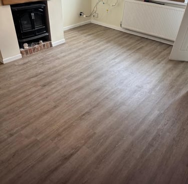 Modern living room featuring light oak wood-effect laminate flooring and a black fireplace stove.