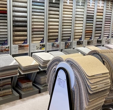 Showroom display featuring a wide variety of carpet samples and flooring textures in neutral tones.