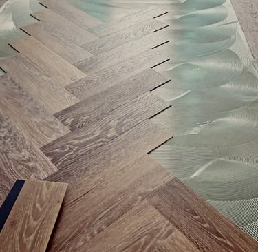 Professional installation of oak herringbone wood flooring onto wet adhesive on a level subfloor.
