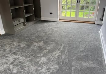 Newly installed plush grey carpet in a bedroom with built-in wardrobes and glass patio doors.