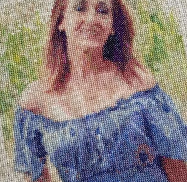 Retrato detallado y personalizado en punto de cruz de una mujer sonriente con un vestido azul  