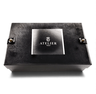 Elegant black Atelier 1951 luxury gift box with silver logo and gold stud accents.