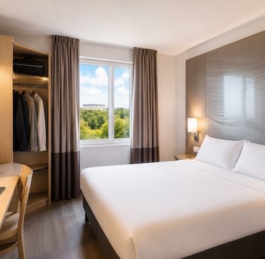 Modern B&B Hotel room featuring a double bed, wooden desk with laptop, and scenic window view.