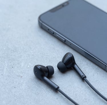 A close-up shot of a modern smartphone and wireless earbuds resting on a light blue concrete surface, representing mobility and modern tech consulting. Minimalist composition, clean lighting, North American tech style, professional and sophisticated, high detail.