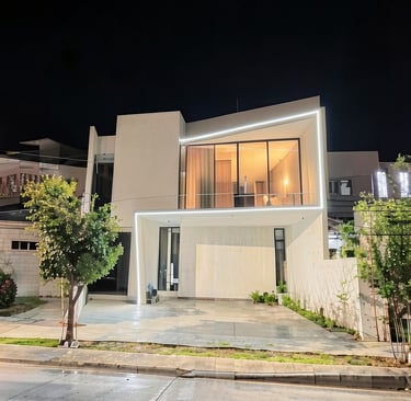 Fachada minimalista con iluminación arquitectónica y líneas de luz continuas.