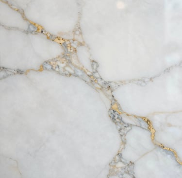 Stacks of granite slabs in varied earth tones, neatly arranged in a sunlit warehouse.