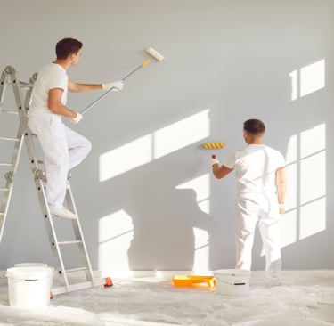 a man and woman painting a wall in a room