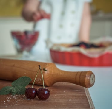 Fresh cherries and a wooden rolling pin on a table for homemade baking.