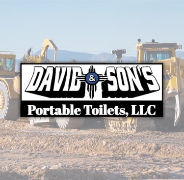 Heavy construction machinery at a desert work site with David and Son's Portable Toilets logo.