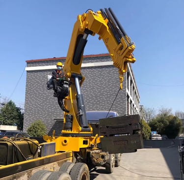 A large object being raised by a crane, specifically a 25 Ton Knuckle Loader Crane.