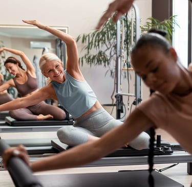 a woman is doing reformer pilates in a group fitness class