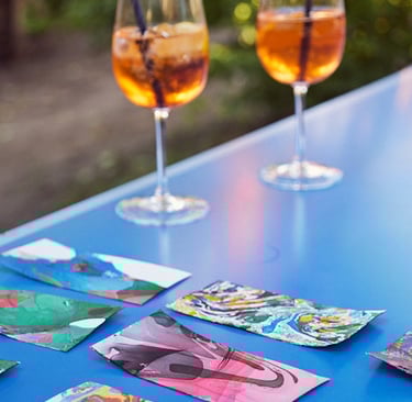 Aperol Spritz Glasses on a blue table with artwork.