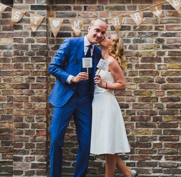 Frischvermählte vor einer Backsteinmauer.