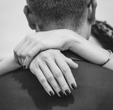 Die Hände der Braut auf den Schultern des Bräutigams.