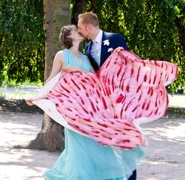 Braut und Bräutigam halten ein ausgeschnittenes Herz in den Händen.