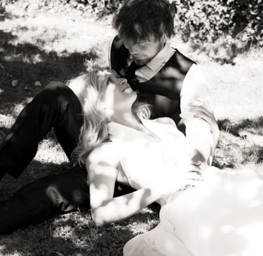 Braut und Bräutigam liegen auf dem Rasen und schauen sich an.