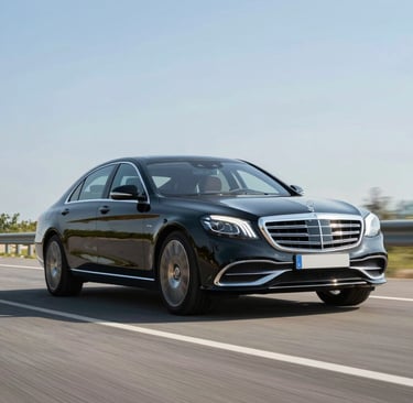 A sleek black luxury car parked by a scenic Northern Ireland coastline at sunset.