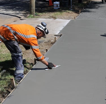 a man in a helmet and safety vest is  working on a wet concrete