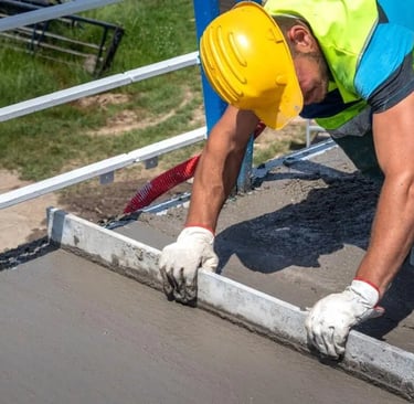 a man in a yellow safety vest is ldoing concrete floor