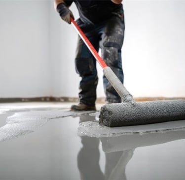 a man is applying floor epoxy with a roller 
