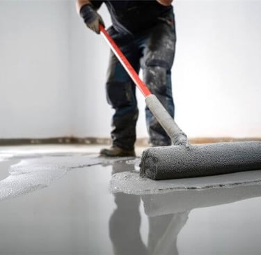a man is applying floor epoxy with a roller