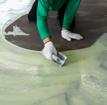 a person in a green shirt is applying an epoxy in a concrete floor