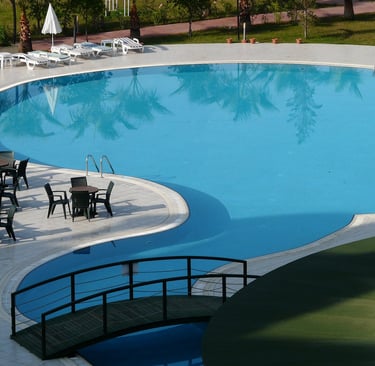 a pool with chairs and tables in a resort