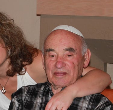 A smiling woman hugging an elderly man wearing a white yarmulke at a family gathering.