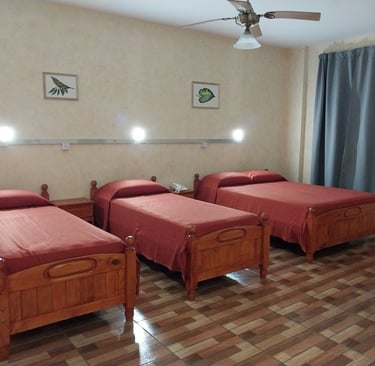 Una habitación con tres camas y un ventilador de techo.