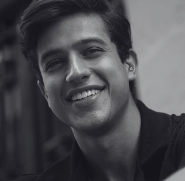 Man taking selfie with genuine smile while sitting, natural lighting with a friendly expression