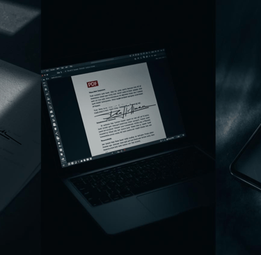 Digital signature displayed on a laptop screen, paper document, and smartphone for electronic branding.