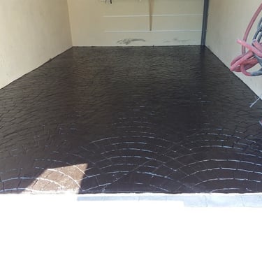 Superficie de hormigón impreso en color negro con diseño semicircular, ideal para parkings y zonas de almacenamiento."