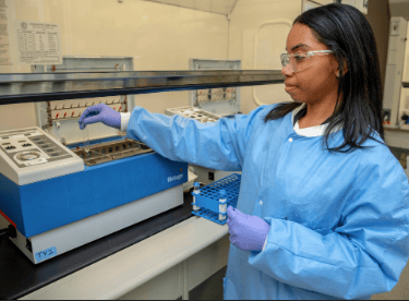 a woman in a lab coat and gloves holding a device
