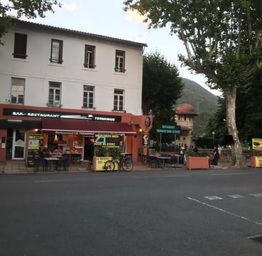 Charming sidewalk terrace of Le Terminus French bar and restaurant in a scenic Quillan.