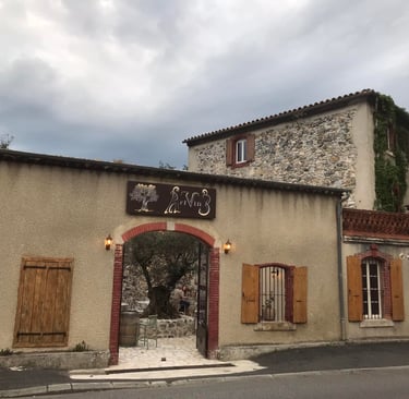 Rustic French stone building and wine bar entrance with wooden shutters in Quillan.