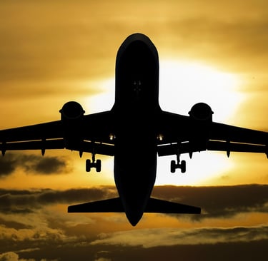 a plane flying in the sky at sunset