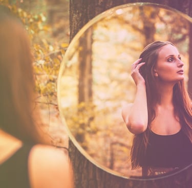 a woman in a black dress standing in front of a mirror