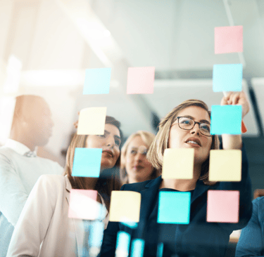 a group of people standing around a post - it notes on a sticky note pad