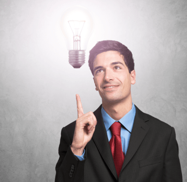 a man in a suit and tie is pointing at a light bulb