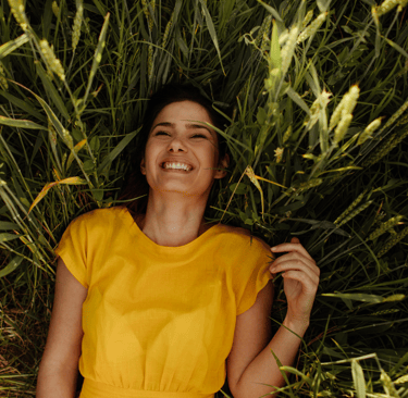 a woman in a yellow dress smiling and holding a flower
