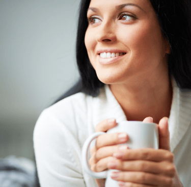 a woman holding a cup of coffee and smiling
