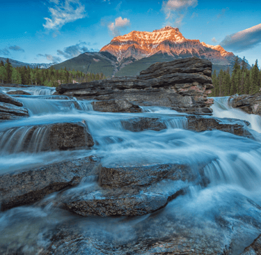 a mountain stream running through a valley with a mountain in the background
