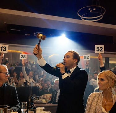 Gala Auctioneer Craig Rosie leading a high-energy Paddle Raise with multiple donor paddles