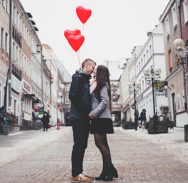 San Valentín, Una Pareja a punto de besarse en medio de la calle, con globos de corazón al fondo